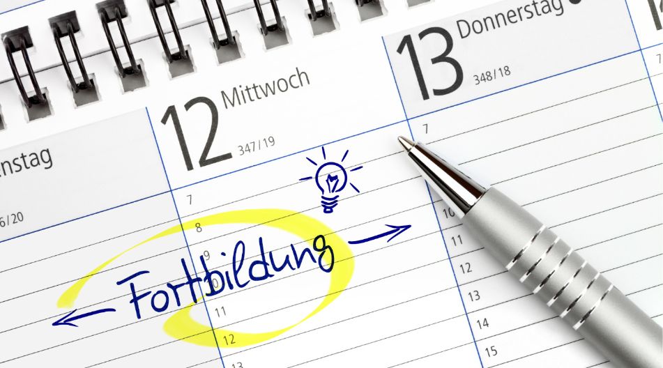 Ein Kalenderblatt mit den Daten Mittwoch, 12., und Donnerstag, 13.; der Eintrag "Fortbildung" ist handschriftlich eingetragen und gelb markiert, daneben ein gezeichneter Glühbirnen-Sketch. Ein silberner Kugelschreiber liegt auf dem Kalender. Ein Kalenderblatt mit den Daten Mittwoch, 12., und Donnerstag, 13.; der Eintrag "Fortbildung" ist handschriftlich eingetragen und gelb markiert, daneben ein gezeichneter Glühbirnen-Sketch. Ein silberner Kugelschreiber liegt auf dem Kalender.