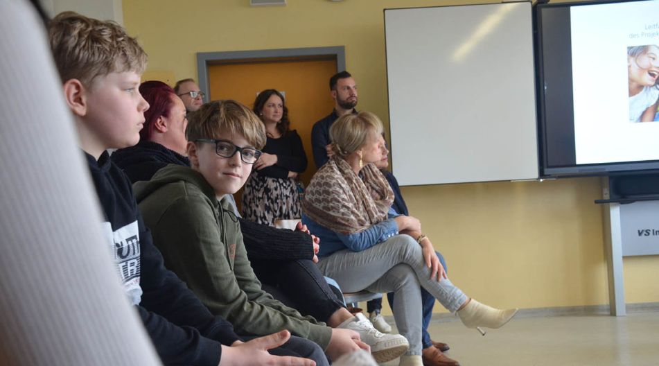 Projekt Gemeinsam Klasse sein der 6c der Werner-von-Siemens-Schule Mehrere Menschen sitzen zusammen vor einem Bildschirm und diskutieren die Informationen, die darauf angezeigt werden.