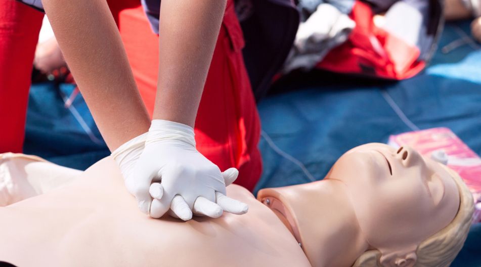 Eine Person übt an einer Reanimationspuppe eine Herzdruckmassage, trägt dabei Handschuhe. Eine Person übt an einer Reanimationspuppe eine Herzdruckmassage, trägt dabei Handschuhe.