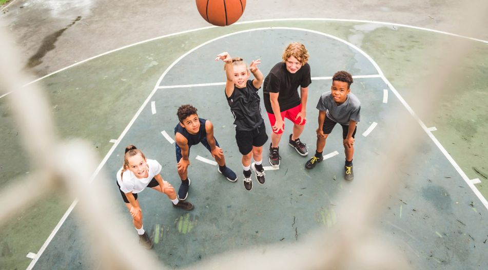 Kinder werfen einen Basketball in Richtung des Korbes. Die Kamera hängt an dem Korb und nimmt das Foto aus der Perspektive des Ringes auf. Kinder werfen einen Basketball in Richtung des Korbes. Die Kamera hängt an dem Korb und nimmt das Foto aus der Perspektive des Ringes auf.