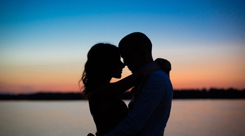Silhouette eines Paares, das sich bei Sonnenuntergang umarmt, mit warmen Farben des Himmels im Hintergrund. Silhouette eines Paares, das sich bei Sonnenuntergang umarmt, mit warmen Farben des Himmels im Hintergrund.