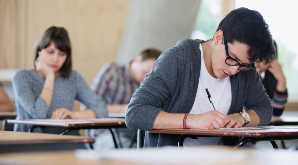 Mehrere Studierende sitzen in einem Prüfungsraum an Tischen und schreiben konzentriert eine Klausur. Mehrere Studierende sitzen in einem Prüfungsraum an Tischen und schreiben konzentriert eine Klausur.