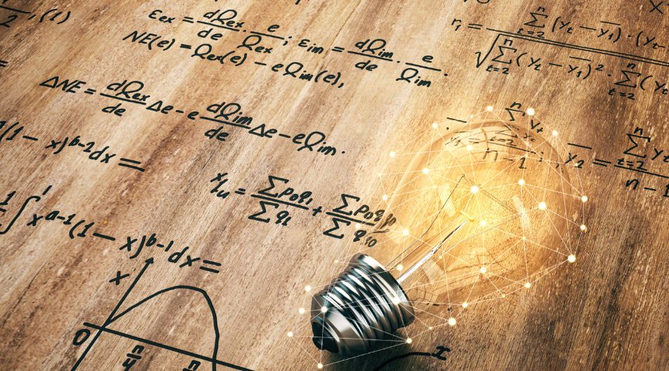 Auf einem Tisch befindet sich eine Glühbirne, die von verschiedenen mathematischen Formeln umgeben ist Auf einem Tisch befindet sich eine Glühbirne, die von verschiedenen mathematischen Formeln umgeben ist