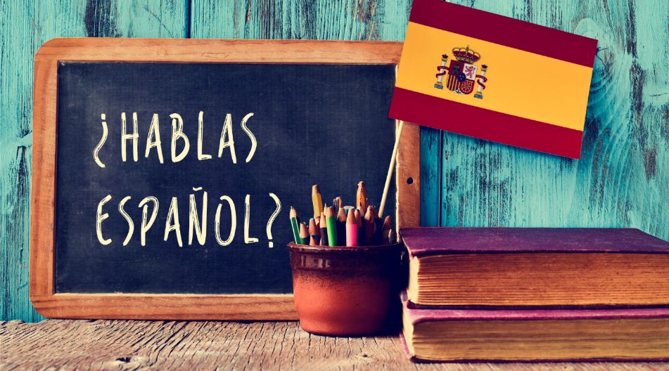 Ein Bild mit einer Schiefertafel, auf der '¿Hablas español?' steht, einer spanischen Flagge, einem Topf mit bunten Stiften und zwei Büchern, symbolisiert das Lernen und Sprechen der spanischen Sprache. Ein Bild mit einer Schiefertafel, auf der '¿Hablas español?' steht, einer spanischen Flagge, einem Topf mit bunten Stiften und zwei Büchern, symbolisiert das Lernen und Sprechen der spanischen Sprache.